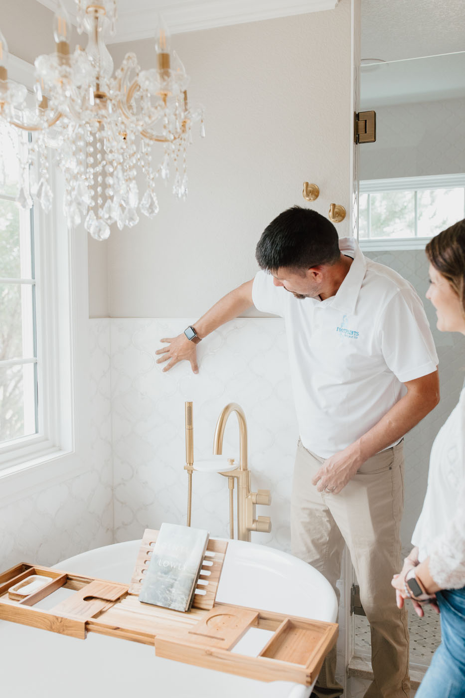 A Footprints Bath and Tile associate displaying the finishing touches of a guest bathroom remodel with a homeowner.