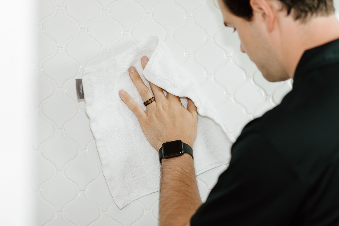 A Footprints Bath and Tile employee giving a thorough cleanup to a tile wall after a reconstruction project.