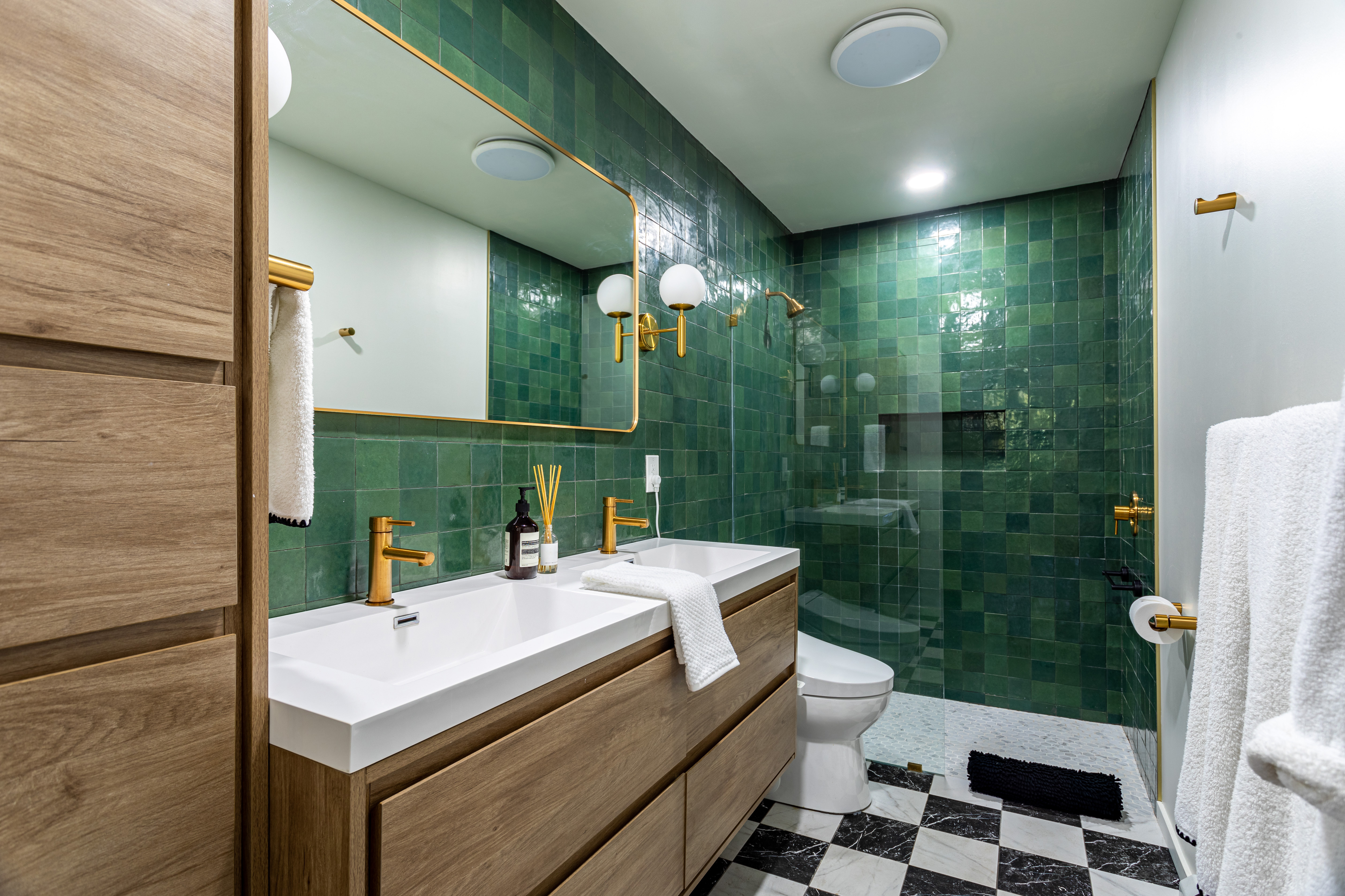 A stunning bathroom with green tiled walls and brown cabinetry used for storage in Richmond, VA.