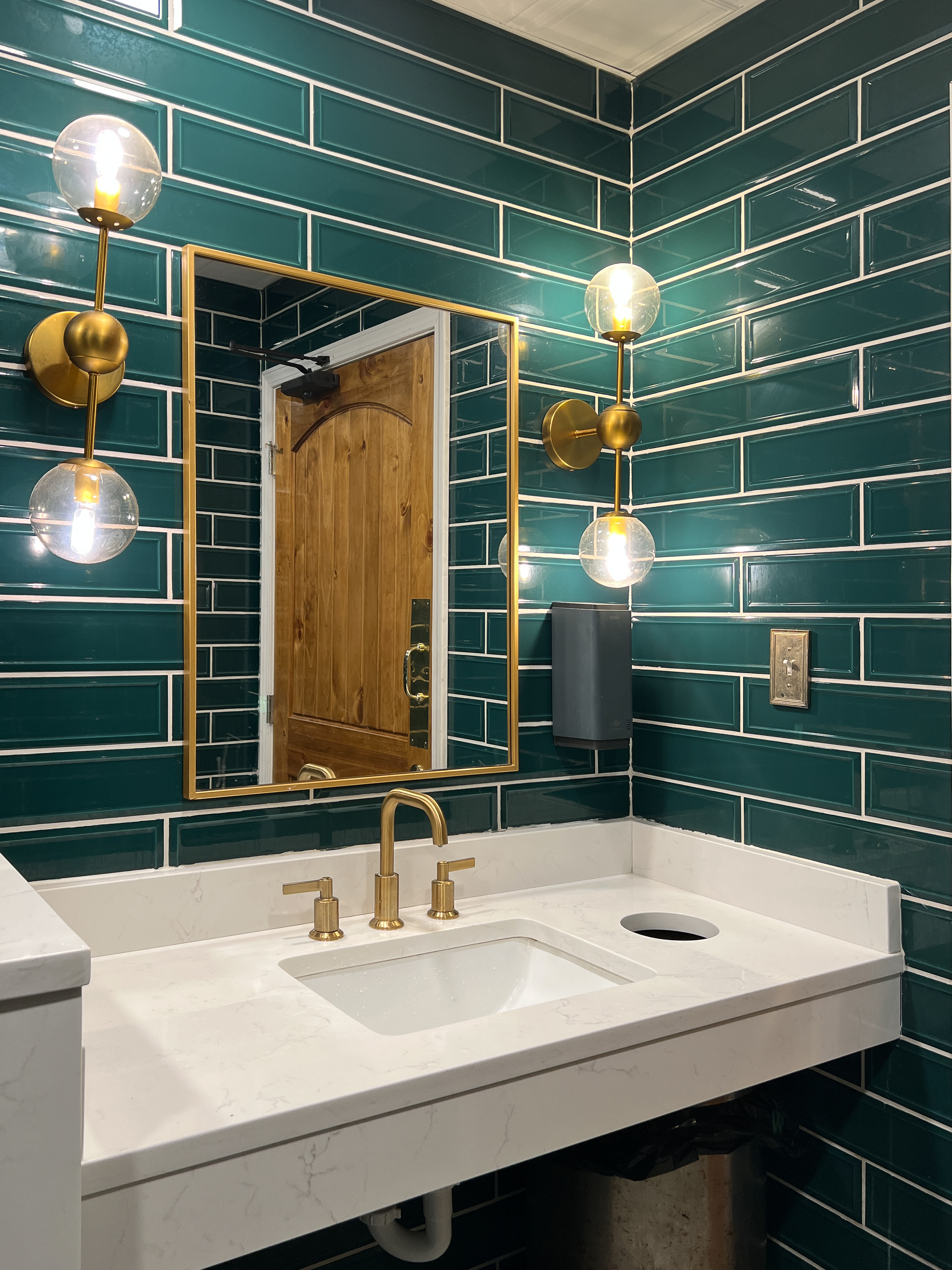 A powder room renovation from Footprints Bath and Tile with shiny new green tiled walls.